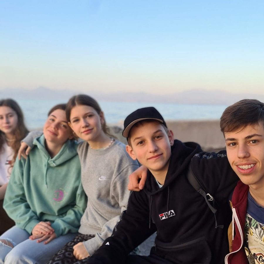 Grup de adolescenți stând împreună pe o plajă, la apus
